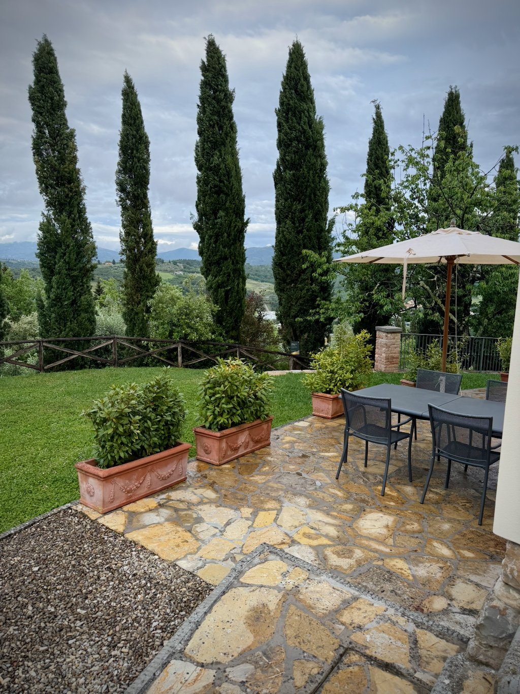 A stone terrace with cypresses overlooking the Chianti hills