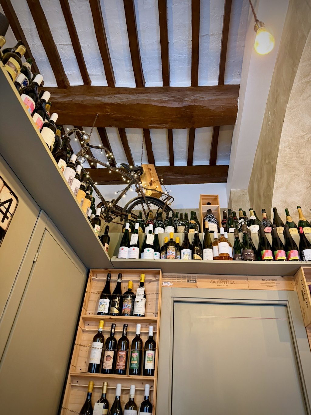 Bottles stacked to the beamed ceiling of an enoteca in Montepulciano